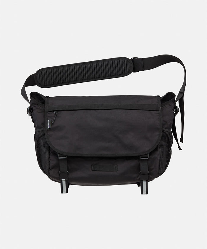 Black Gramicci Messenger Bag on a  light tone background.