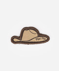 An embroidered patch shaped like a cowboy hat, featuring a tan center with a dark brown stitched border and script text reading 'Gigi Pipi' on the right side, set against a plain light gray background #color_tan