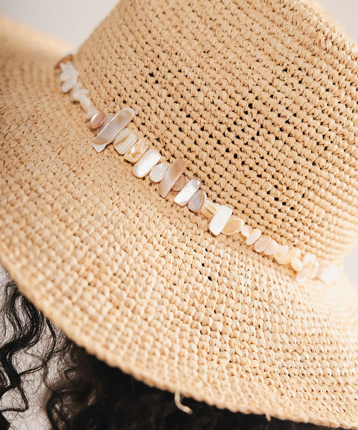 Close-up of a straw hat with decorative shells on a plain background #color_natural