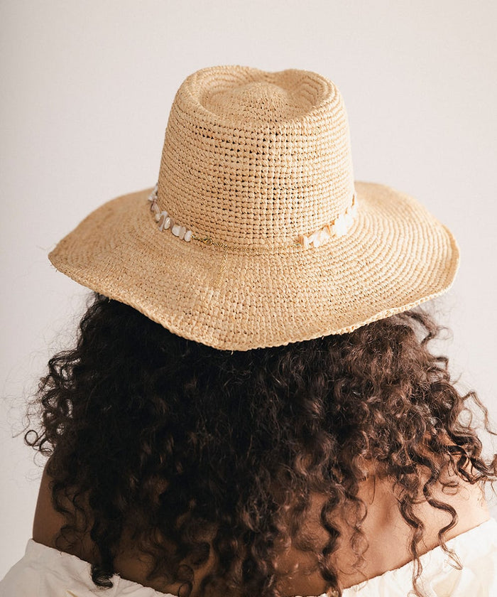 Woman wearing a straw hat with a decorative band in a plain background #color_natural