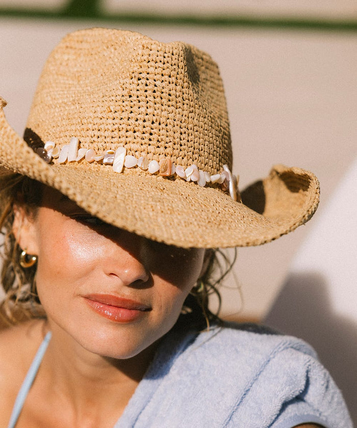 Woman wearing a straw hat with a decorative band outdoors #color_natural