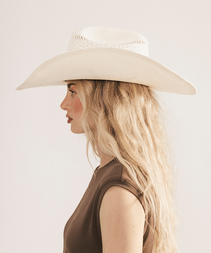 Woman wearing a straw cowboy hat against a plain background #color_natural white