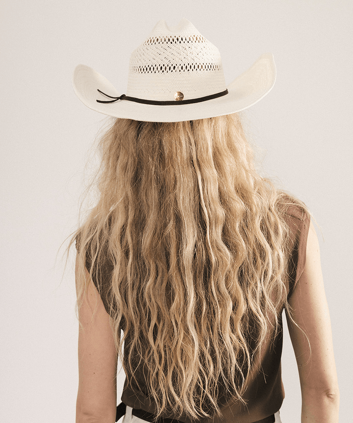 Woman wearing a straw cowboy hat against a plain background #color_natural white