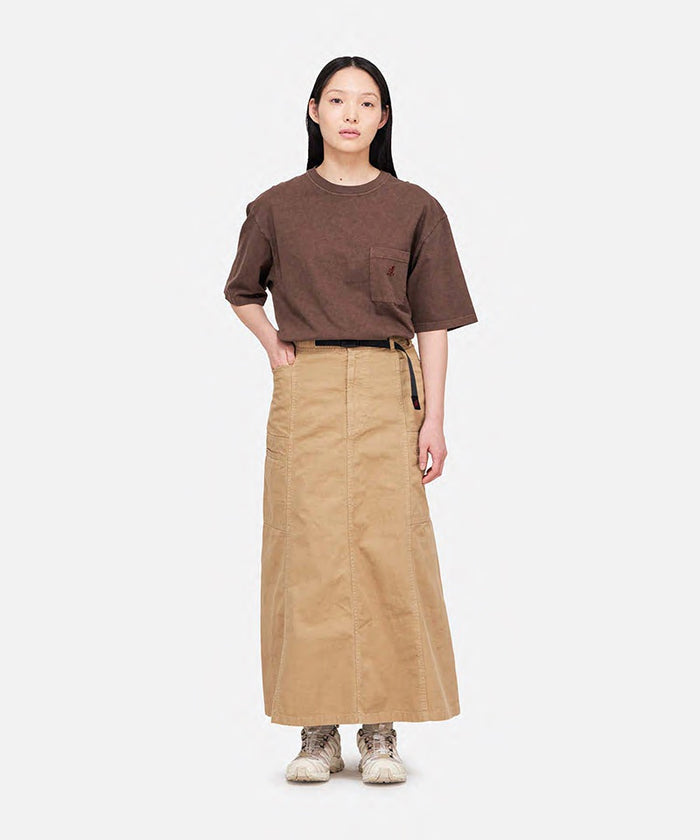 Model wearing a brown pigment Gramicci One Point Tee with a small running man graphic and beige skirt on a light-tone background.