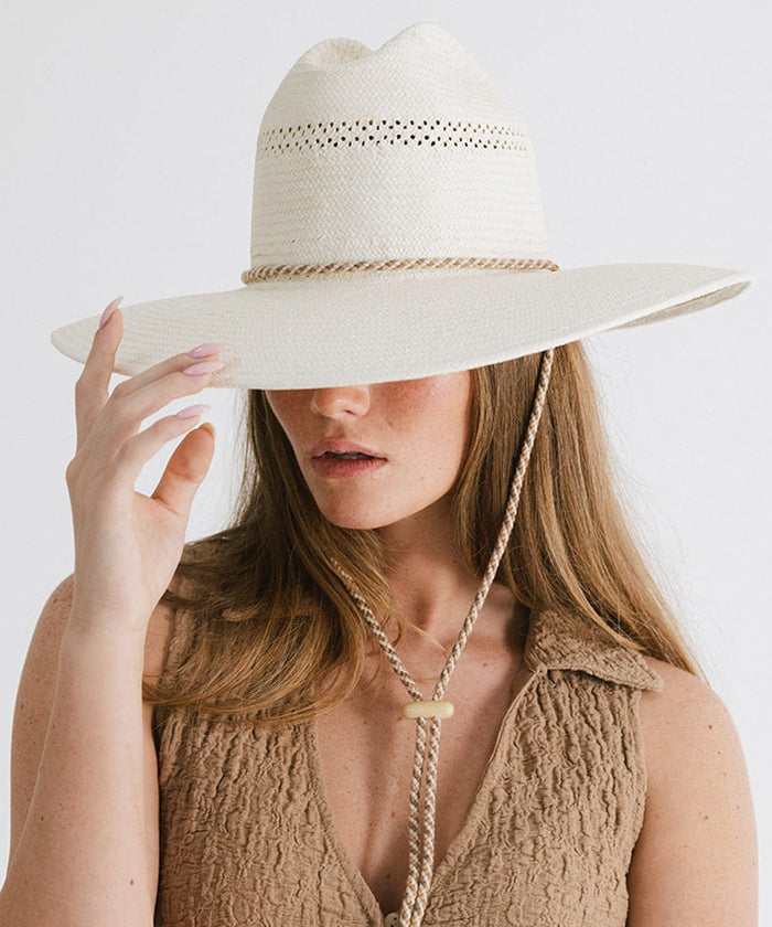 Woman wearing a cream straw hat with a rope hat band and a brown top, posing against a plain background #color_cream