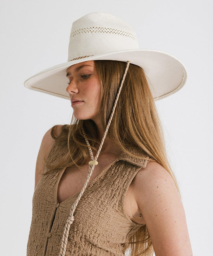 Woman wearing a cream straw hat with a rope hat band and a brown top, facing sideways against a plain background #color_cream