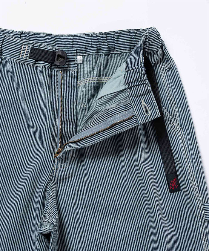 Close-up view of navy Gramicci Overdyed Hickory Work Pants on a light-tone background.