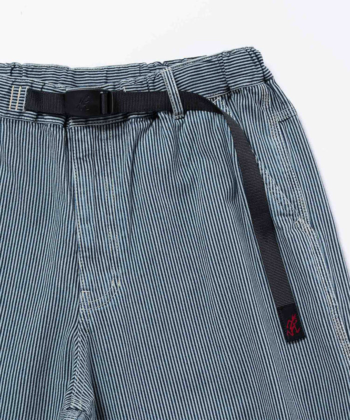 Close-up view of navy Gramicci Overdyed Hickory Work Pants on a light-tone background.