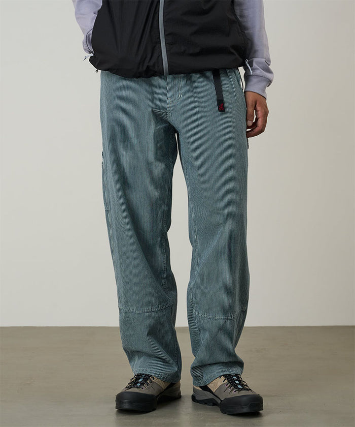 Model wearing navy Gramicci Overdyed Hickory Work Pants and a black vest on a light-tone background.