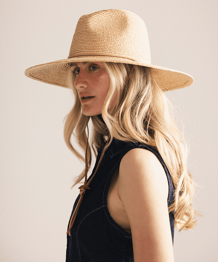Woman wearing a straw hat and denim vest against a plain background #color_natural