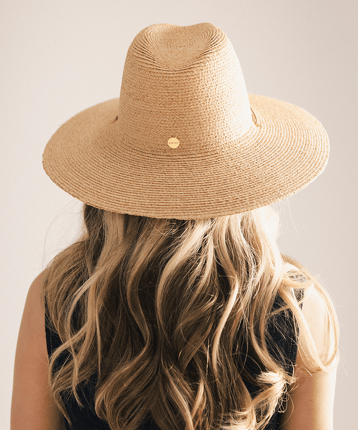Woman wearing a straw hat and denim vest against a plain background #color_natural