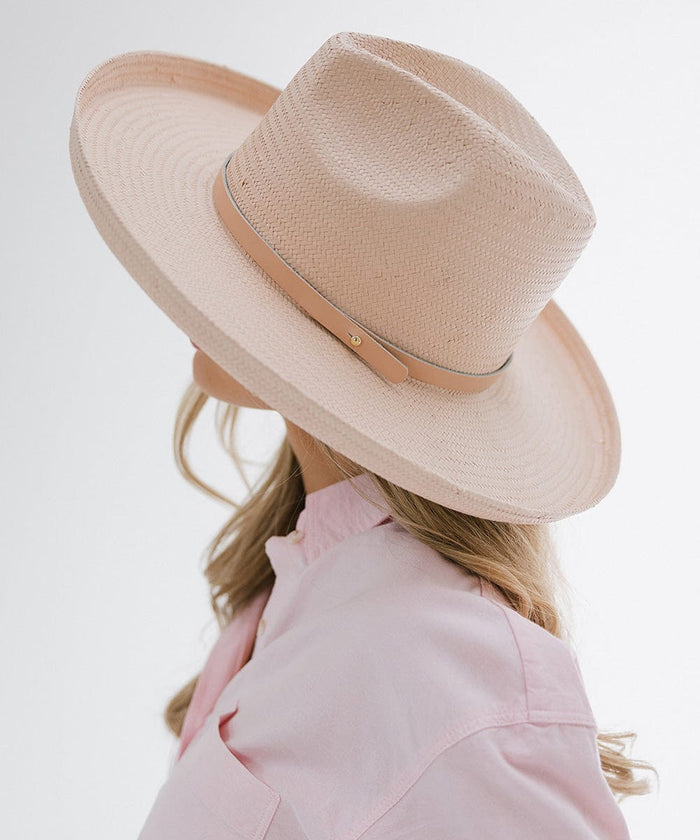 Person wearing a light pink pencil brim straw fedora hat with a hat band, and a pink shirt, facing sideways against a plain background #color_limited edition light pink