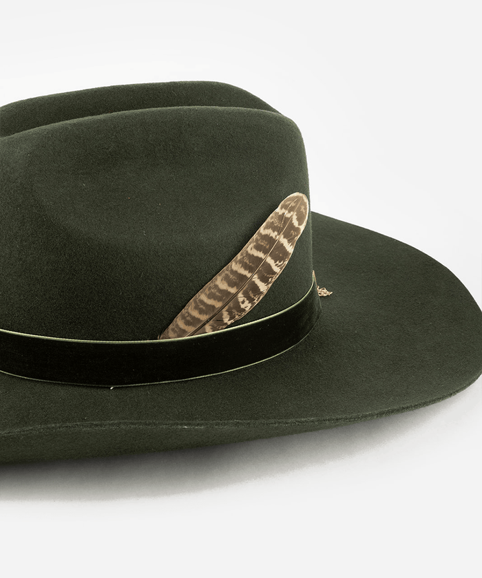 Dark green fedora hat with a brown and cream colored greater prairie chicken hat feather on a plain background #color_brown-cream