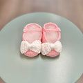 Pink crochet baby booties with white bow.