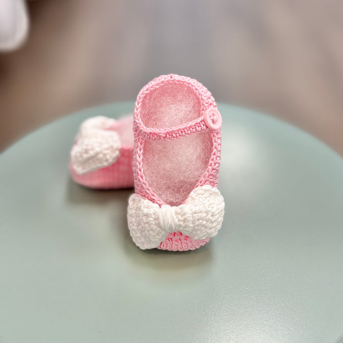 Pink crochet baby booties with white bow.