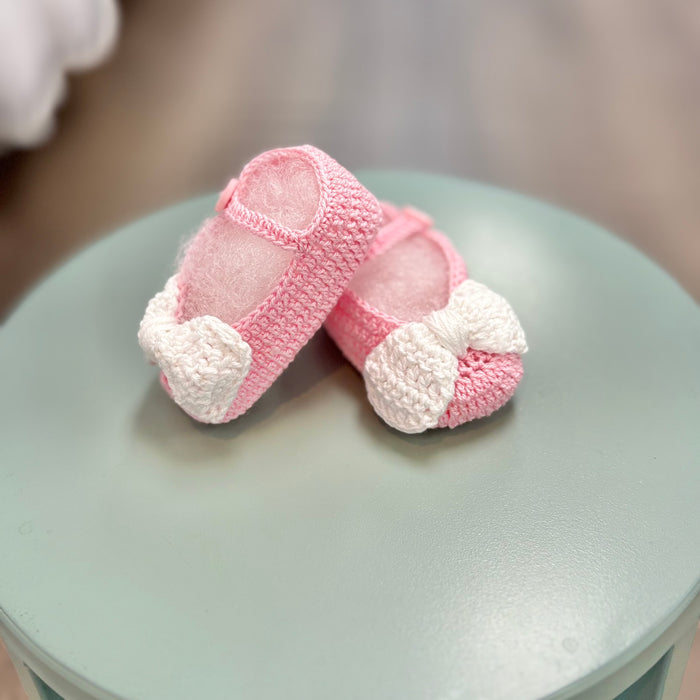 Pink crochet baby booties with white bow.