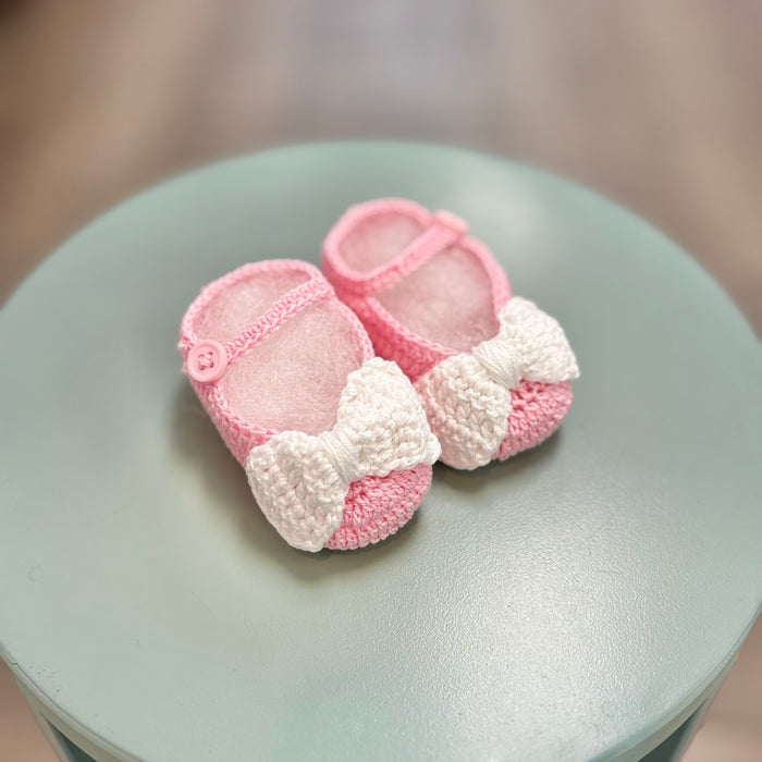 Pink crochet baby booties with white bow.