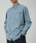 Model wearing a Gramicci blue plaid Poplin Millwood Shirt against a light-tone background.