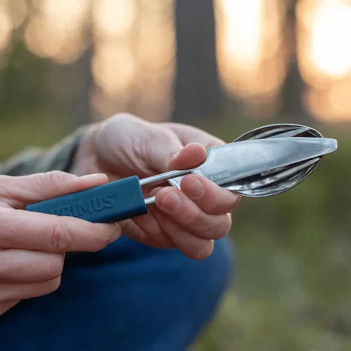 Primus stainless steel leisure cutlery set held in a pair of hands whilst outdoors