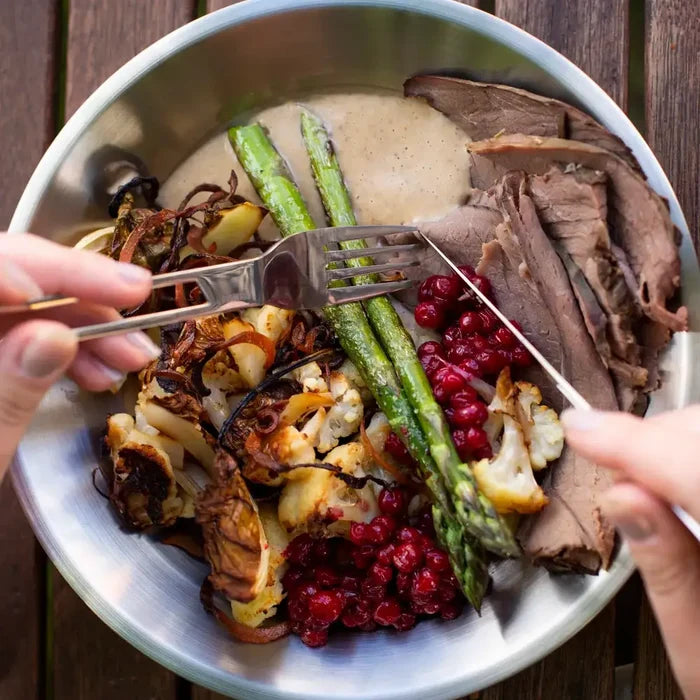 Plate of assorted roasted vegetables and meats being eaten using a Primus Leicesyre stainless steel fork and knife on a wooden table
