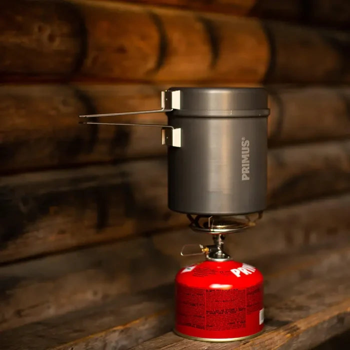 Primus 1000ml Trek pot on top of a camping stove attached to a Power gas canister on a wooden background