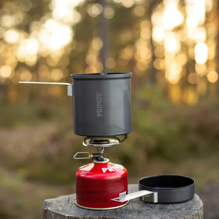 Primus Trek pot being used with a camping gas stove in a forest setting.