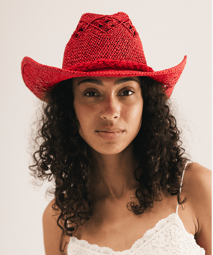 Woman wearing a red crochet cowboy hat against a plain background #color_cherry red