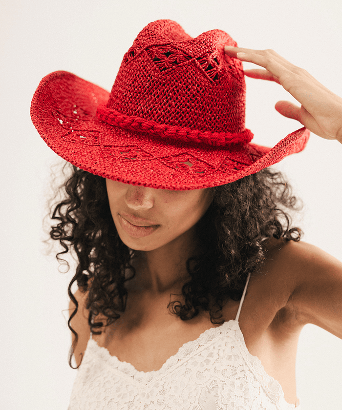 Woman wearing a red crochet cowboy hat against a plain background #color_cherry red