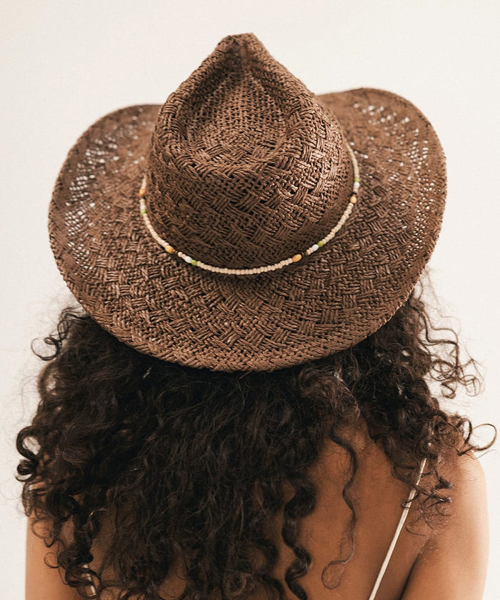 Woman wearing a brown straw hat with a white background #color_chocolate