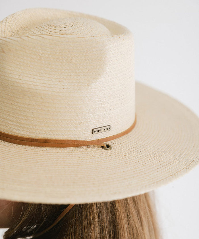 An ivory palm straw sun hat with a teardrop fedora crown and a wide flat brim, featuring a brown genuine leather chinstrap and the brand label #color_ivory