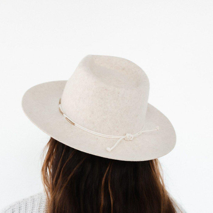 Woman wearing a white hat with a cream rope band with beads facing behind against a plain background #color_cream