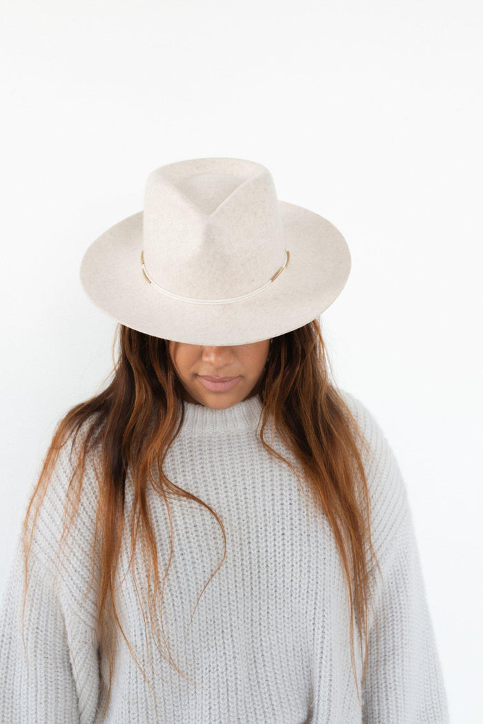 Woman wearing a white hat with a cream rope band with beads and a white sweater against a plain background #color_cream