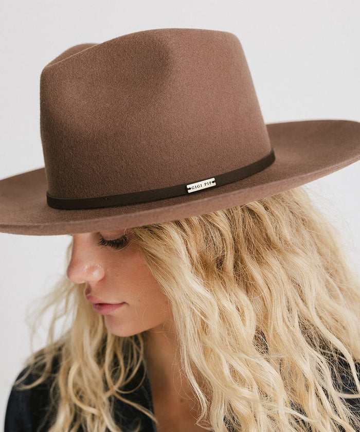 Woman wearing a chocolate colored Rowan Wide Brim Fedora Hat with a hat band against a plain background #color_chocolate