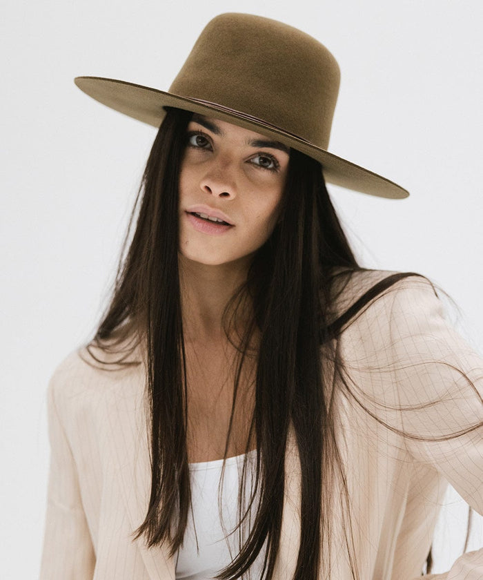 Woman wearing an olive colored open crown hat and a cream blazer against a plain background #color_olive