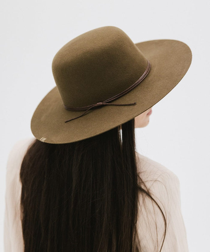 Woman with long hair wearing an olive colored open crown hat with a hat band, looking sideways against a plain background #color_olive