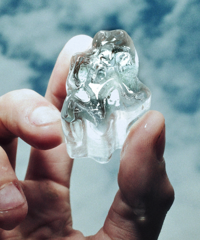 Gramicci running man shaped ice cube held in a hand with a blurred natural background
