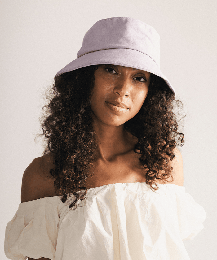 Woman wearing a lavender bucket hat with a plain background #color_lavender
