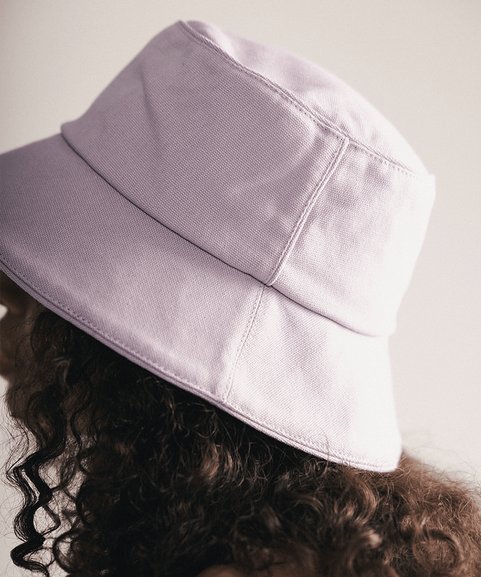 Woman wearing a lavender bucket hat with a plain background #color_lavender