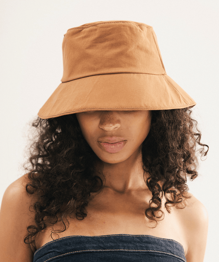 Woman wearing a brown bucket hat with a plain background #color_brown