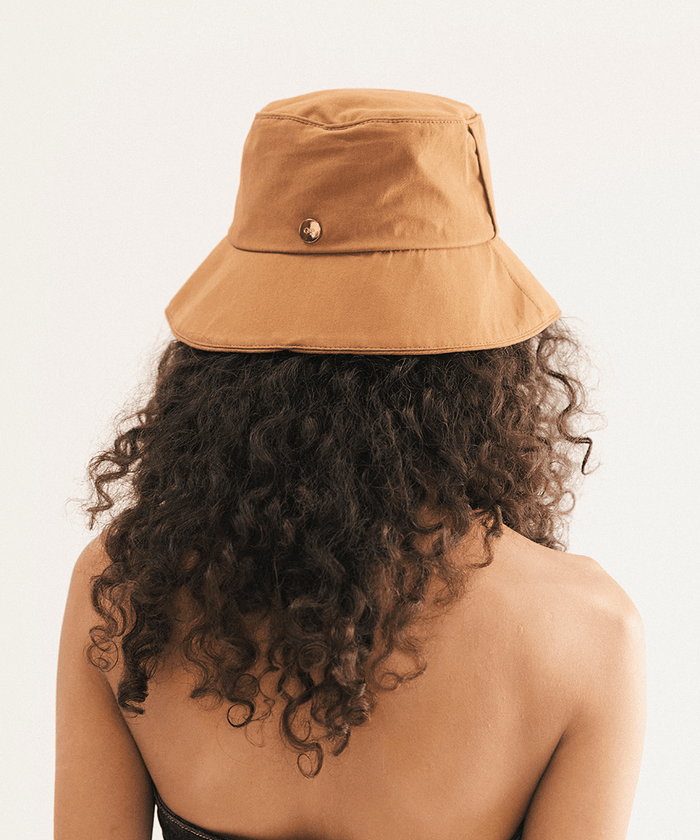 Woman wearing a brown bucket hat with a plain background #color_brown