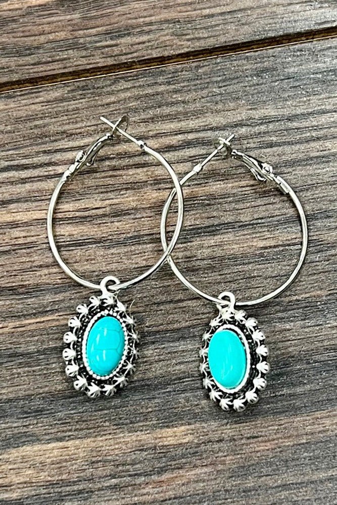 Saddle Stories hoop earrings featuring turquoise oval stones, antique silver western detailing, and lightweight hoop styling for country concert and rodeo outfits.