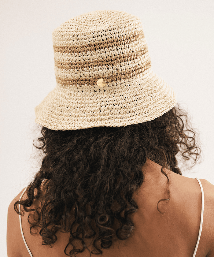 Woman wearing a straw bucket hat against a plain background #color_natural stripe