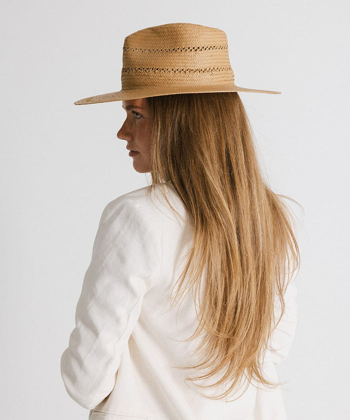 Woman with long hair wearing a honey teardrop straw fedora hat and a white blazer, facing sideways against a plain background #color_honey