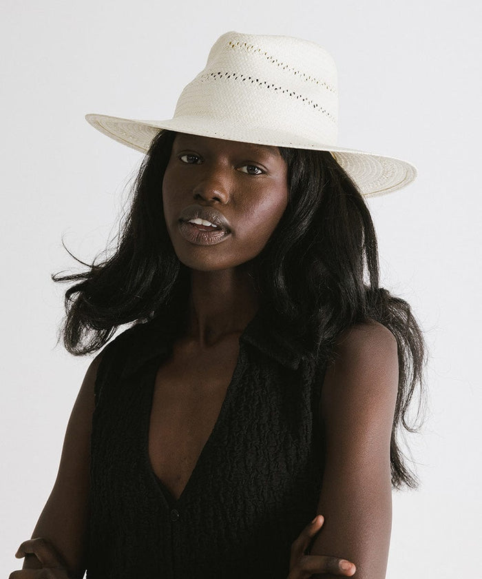 Woman wearing a white straw fedora hat with decorative trim and a black top, posing against a plain background  #color_white