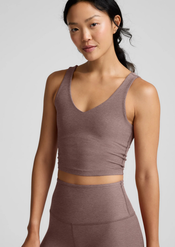Woman wearing a rosey taupe athletic outfit on a plain background