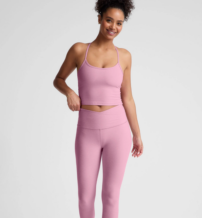 Woman wearing a pink haze athletic outfit on a light gray background
