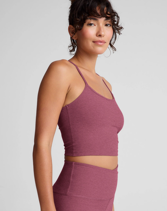 Woman wearing a smooth mauve athletic top and leggings on a light gray background
