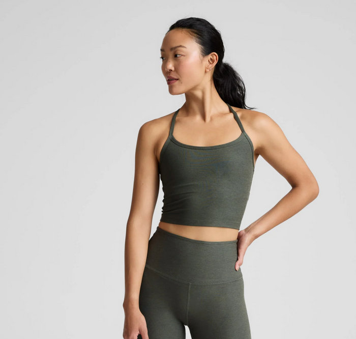 Woman wearing a dusty forest  athletic outfit on a light gray background