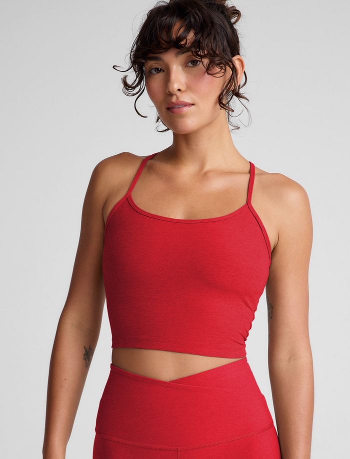 Woman wearing a chili red athletic outfit on a plain background