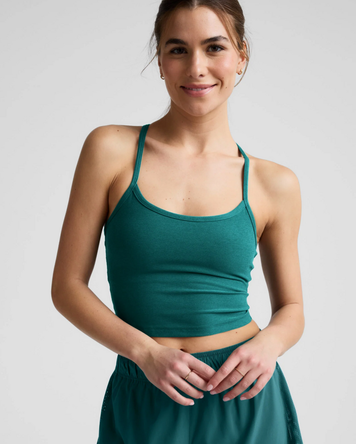 Woman wearing a teal sea athletic outfit on a plain background